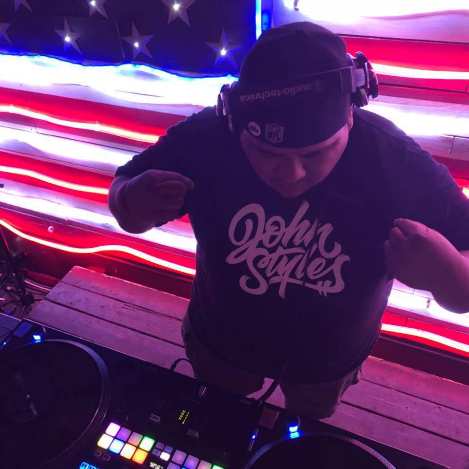 DJ John Styles mixing in front of neon American flag