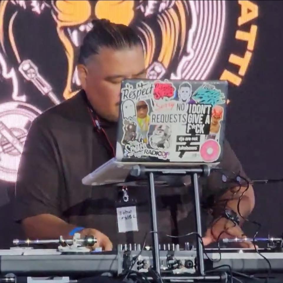 DJ John Styles performing at festival with sticker-covered laptop